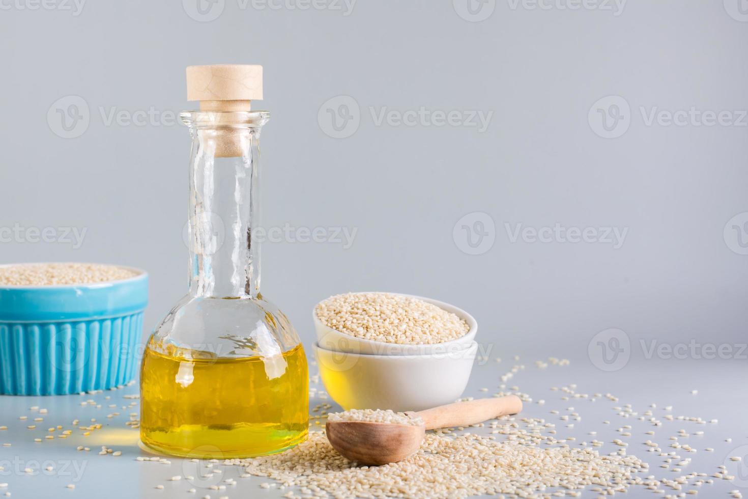 Sesame oil in a bottle and sesame seeds in a bowl on the table. Organic Alternative photo