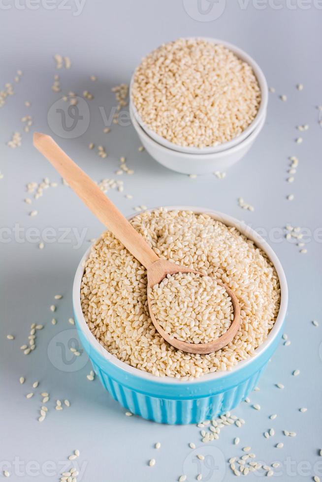 Wooden spoon with sesame seeds in a bowl with sesame seeds. Vitamin nutrition. Vertical view photo