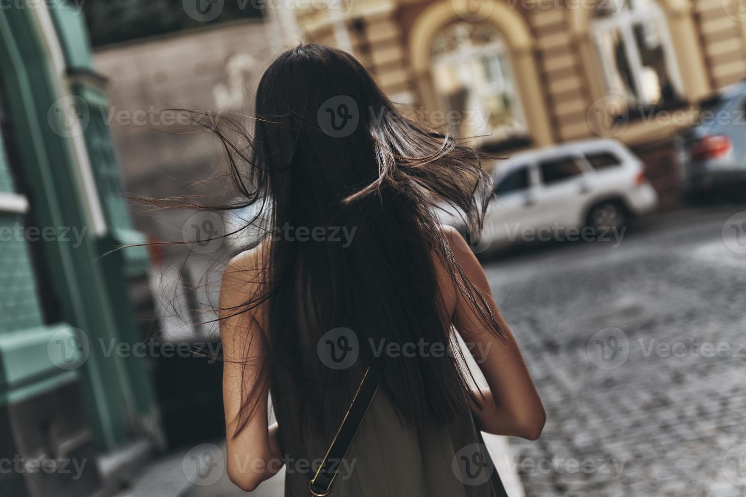 Follow your dream...  Rear view of young woman walking down the street while spending time outdoors photo