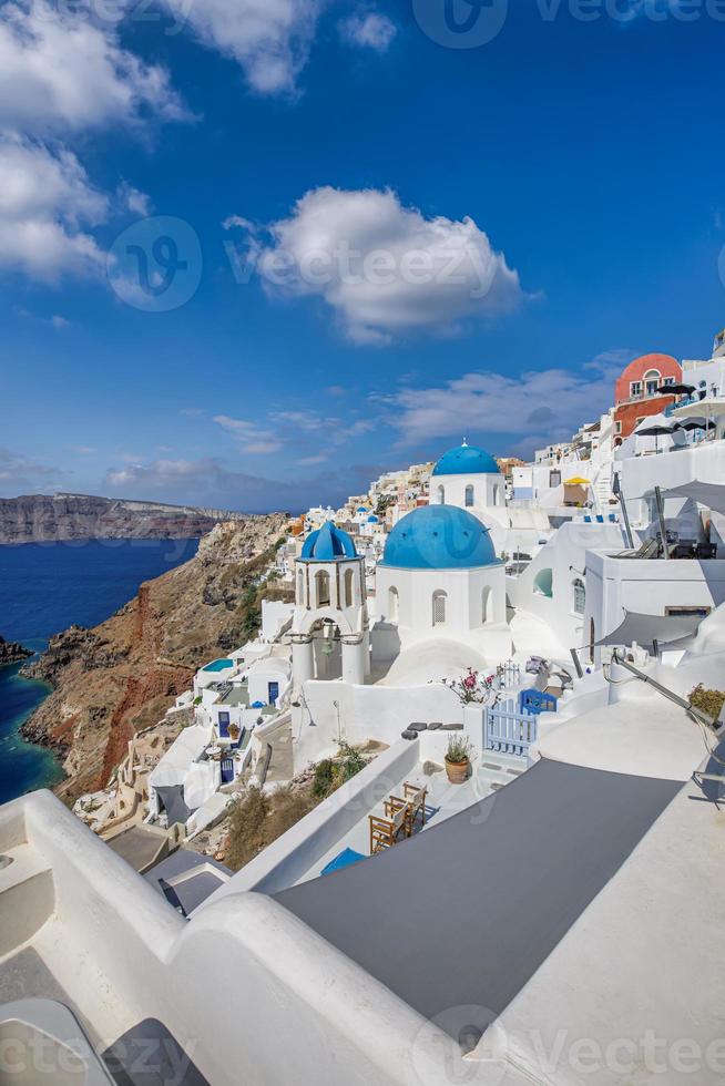 vista de la ciudad de oia en la isla de santorini en grecia. famoso paisaje griego, cúpulas azules sobre arquitectura blanca. destino de vacaciones de verano de lujo, viaje romántico escénico. hermoso paisaje urbano y mar azul foto