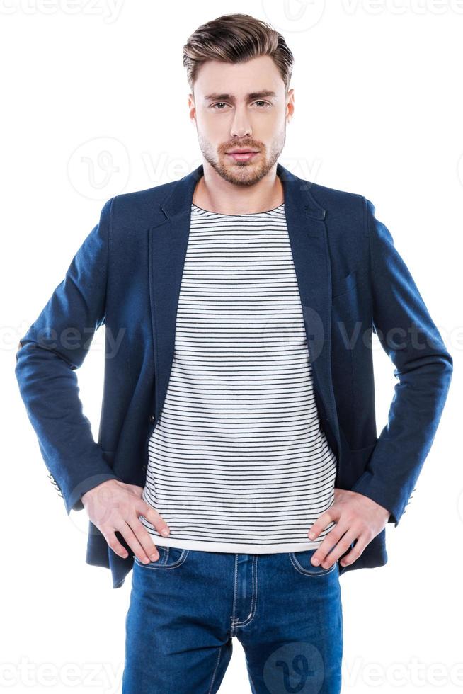 Charming handsome. Handsome young man holding hands on hip and looking at camera while standing against white background photo