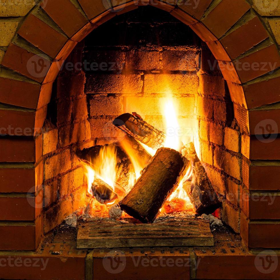 Christmas time, cozy fireplace. Wood logs burning, fire bricks