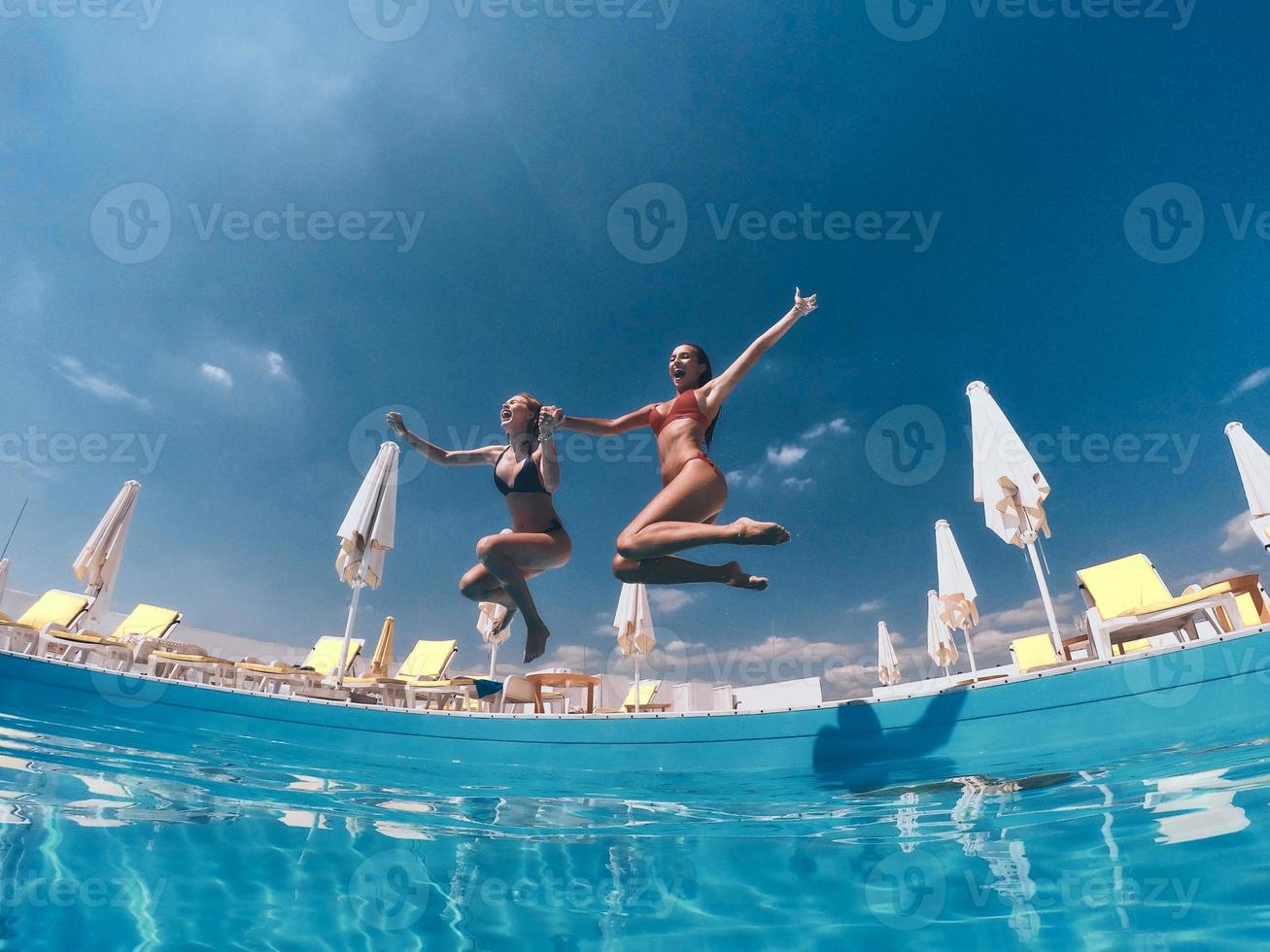 Totally free. Two attractive young women in bikini jumping in the pool together photo