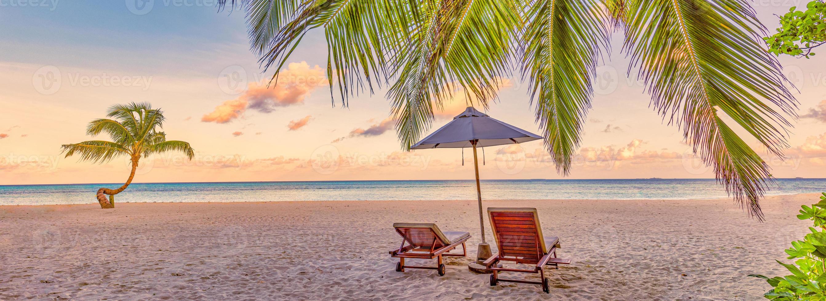 Beautiful tropical sunset landscape, romantic chairs, loungers umbrella stunning palm tree. White sand, sea view horizon, colorful twilight sky, calmness and relaxation. Amazing couple beach resort photo