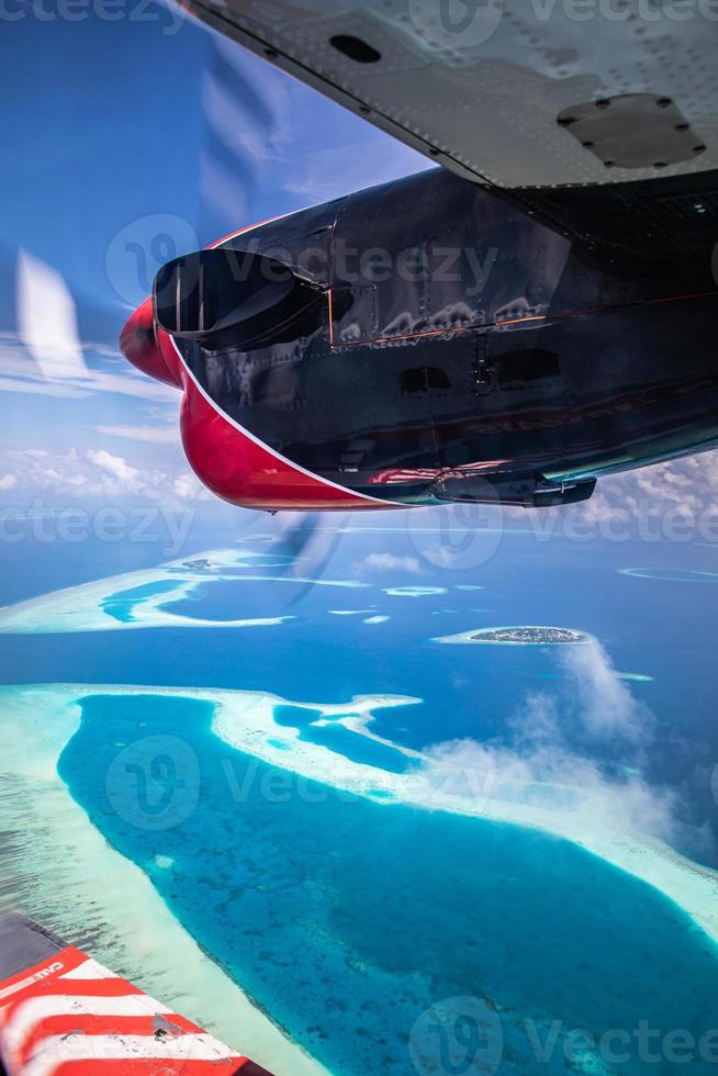 Amazing view from seaplane in Maldives islands, atolls and tropical island resorts from above. Vertical travel landscape, panorama from plane window view. Exotic summer vacation, traveling photo