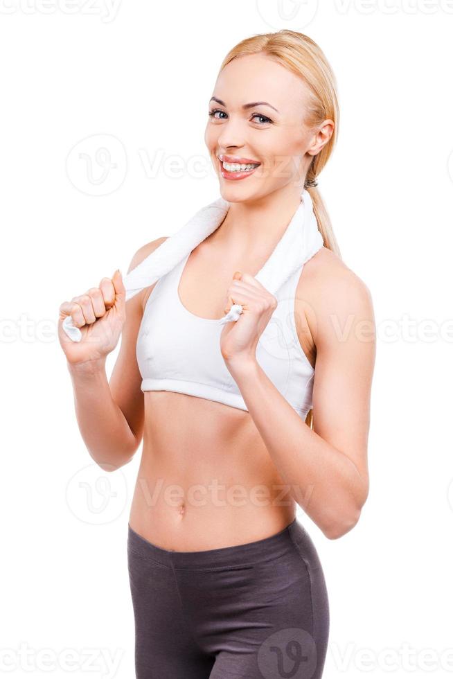 She is fond of sport training. Beautiful mature women adjusting towel on her neck and smiling while standing against white background photo