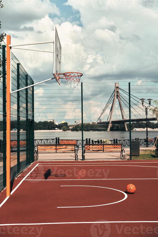 Waiting for players. Shot of basketball ball lying on the empty basketball playground outdoors photo