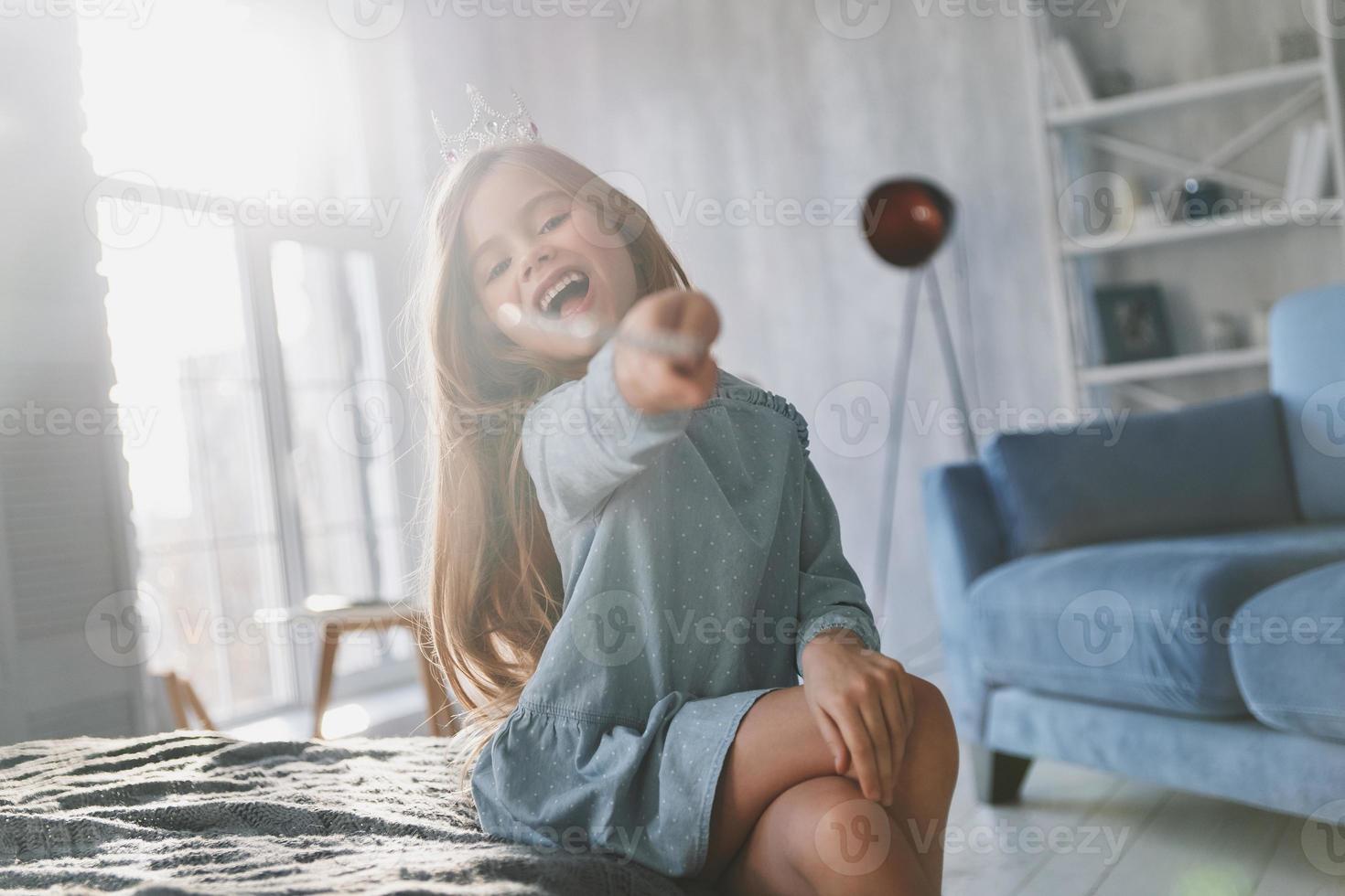 truco de magia. linda niña jugando con una varita mágica y mirando a la cámara mientras pasa tiempo en casa foto