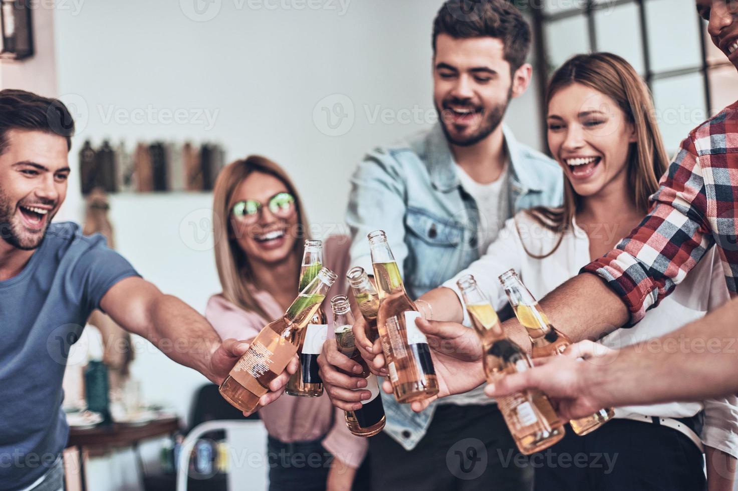 Top view of young people in casual wear gesturing and smiling while having a dinner party indoors photo