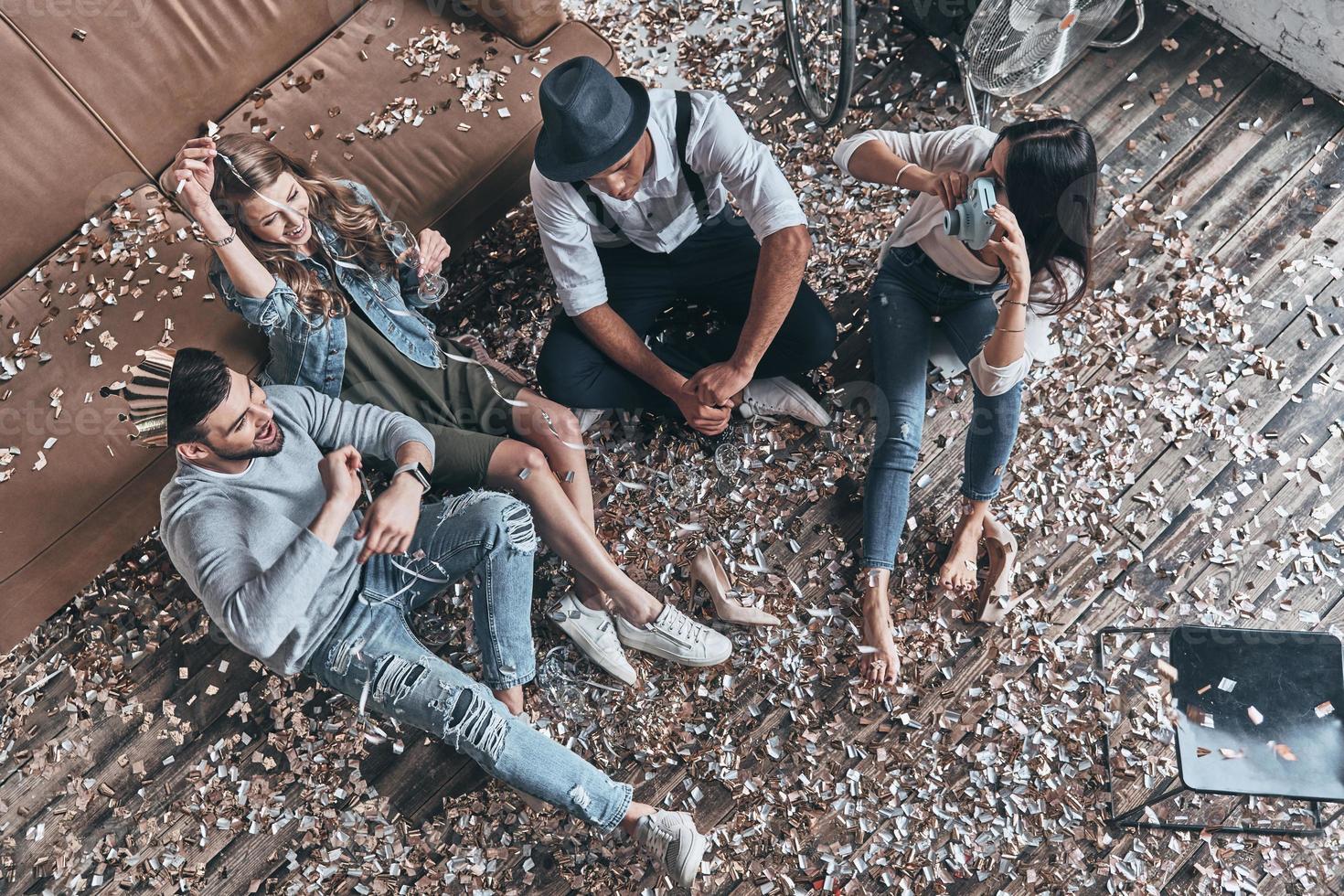 Creating happy memories. Top view of modern young people resting while sitting on the floor with confetti around photo