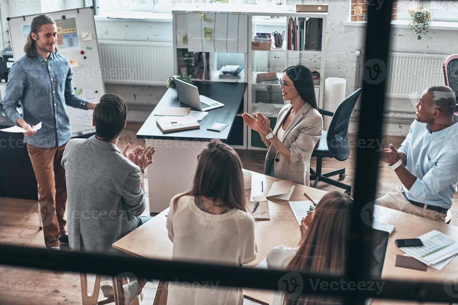 Achieving best results together. Top view of young man conducting a business presentation while standing behind the glass wall in the board room photo