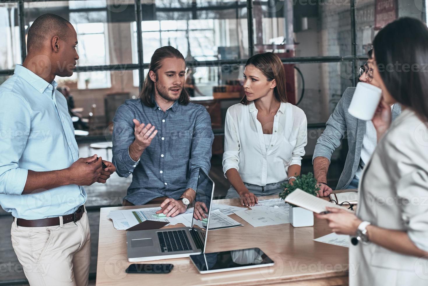 Thinking about every detail. Group of young business people communicating while working in the office photo