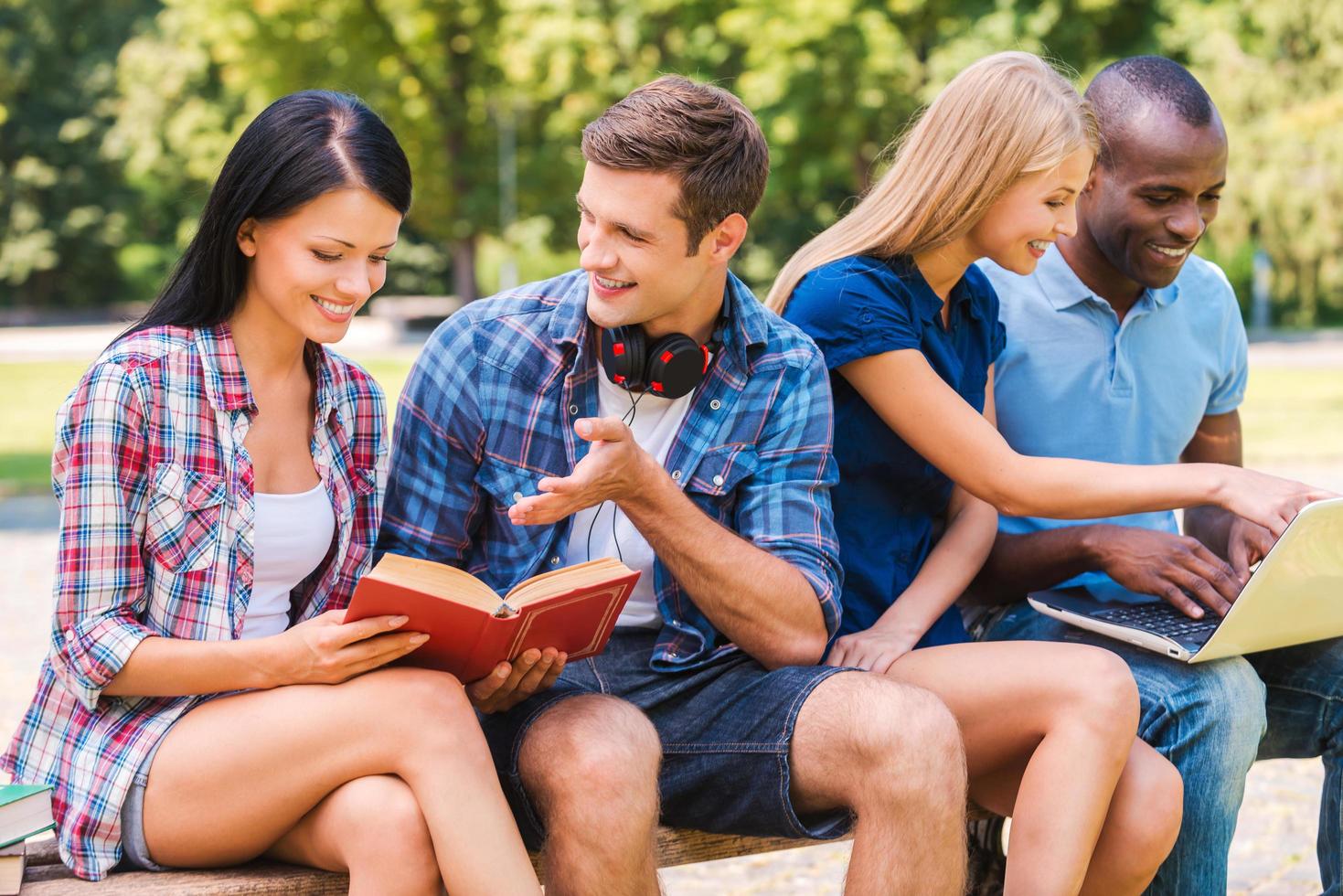 We love spending time together. Four happy young people spending time together while sitting outdoors photo