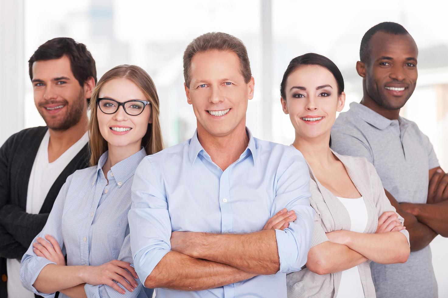 Confident business team. Group of cheerful business people in casual wear standing close to each other and keeping arms crossed photo