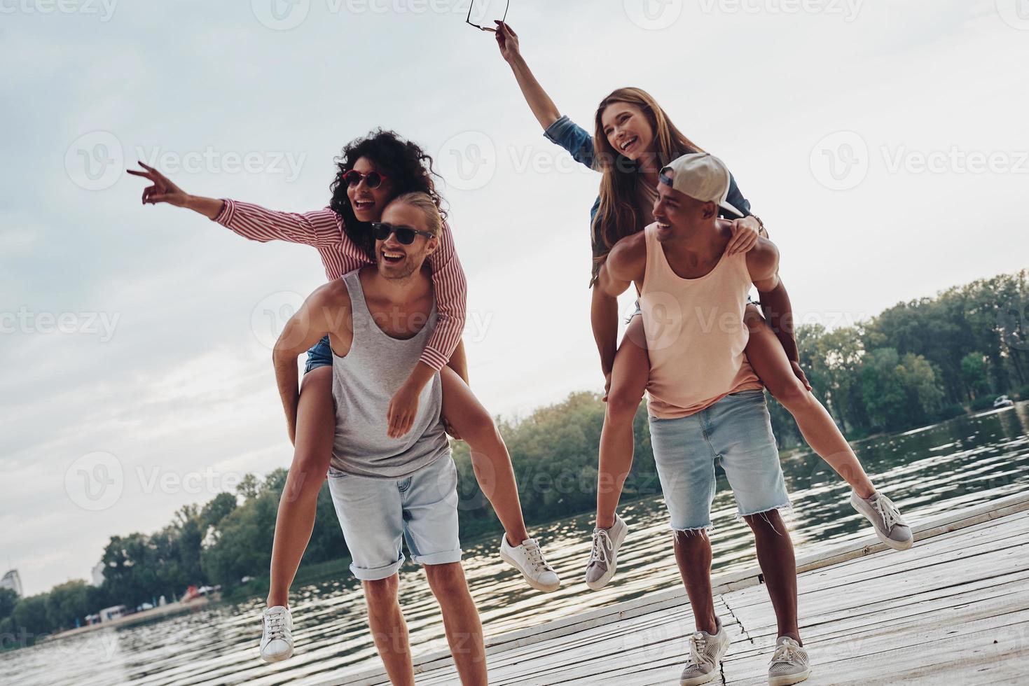 Going crazy. Beautiful young couples spending carefree time while standing on the pier photo