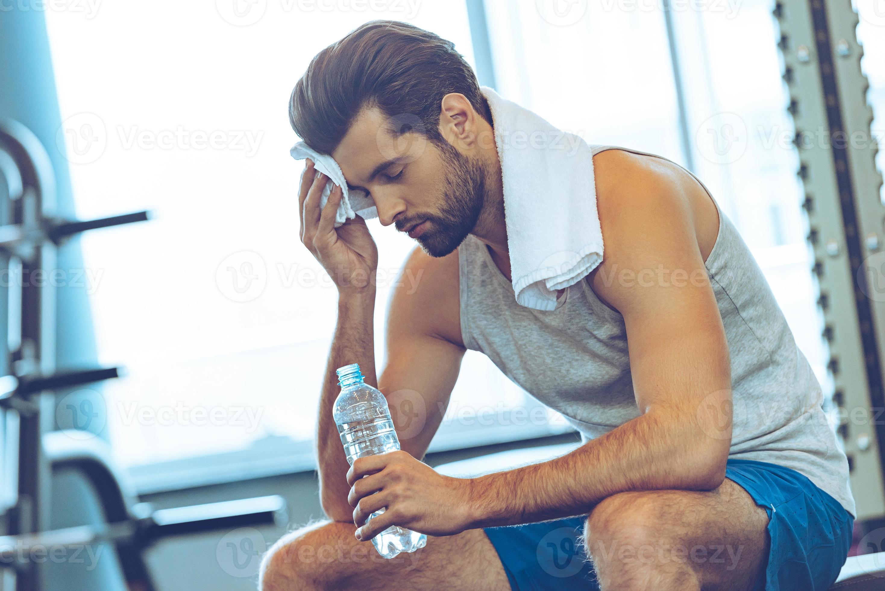 Sweaty after great work out. Handsome young men in sportswear whipping  sweat with his towel and holding water bottle while sitting at gym 13487667  Stock Photo at Vecteezy