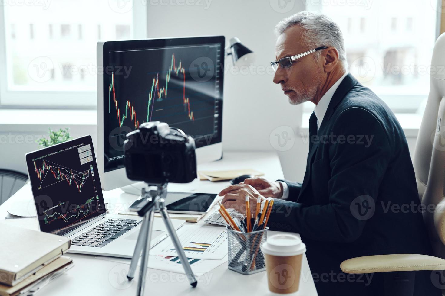 Senior man in elegant business suit using modern technologies while making social media video photo