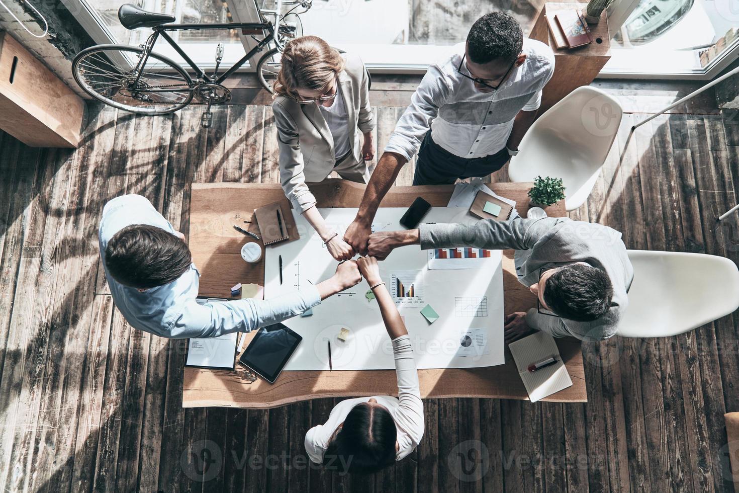 Best team.  Top view of business colleagues holding fists together in a symbol of unity while working in the creative office photo