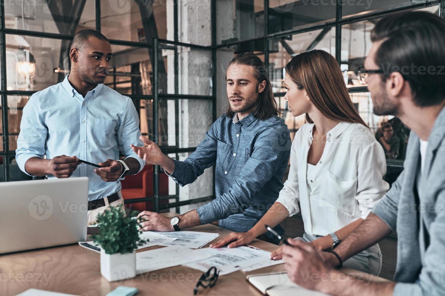 Ready to work hard. Group of young business people discussing something while sitting in the office photo