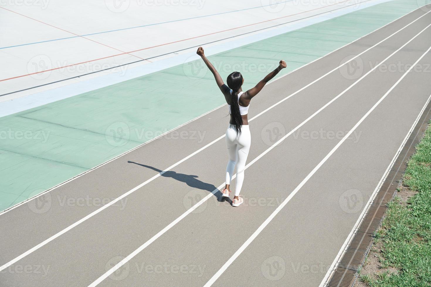 vista superior de una hermosa joven africana vestida con ropa deportiva manteniendo los brazos levantados foto