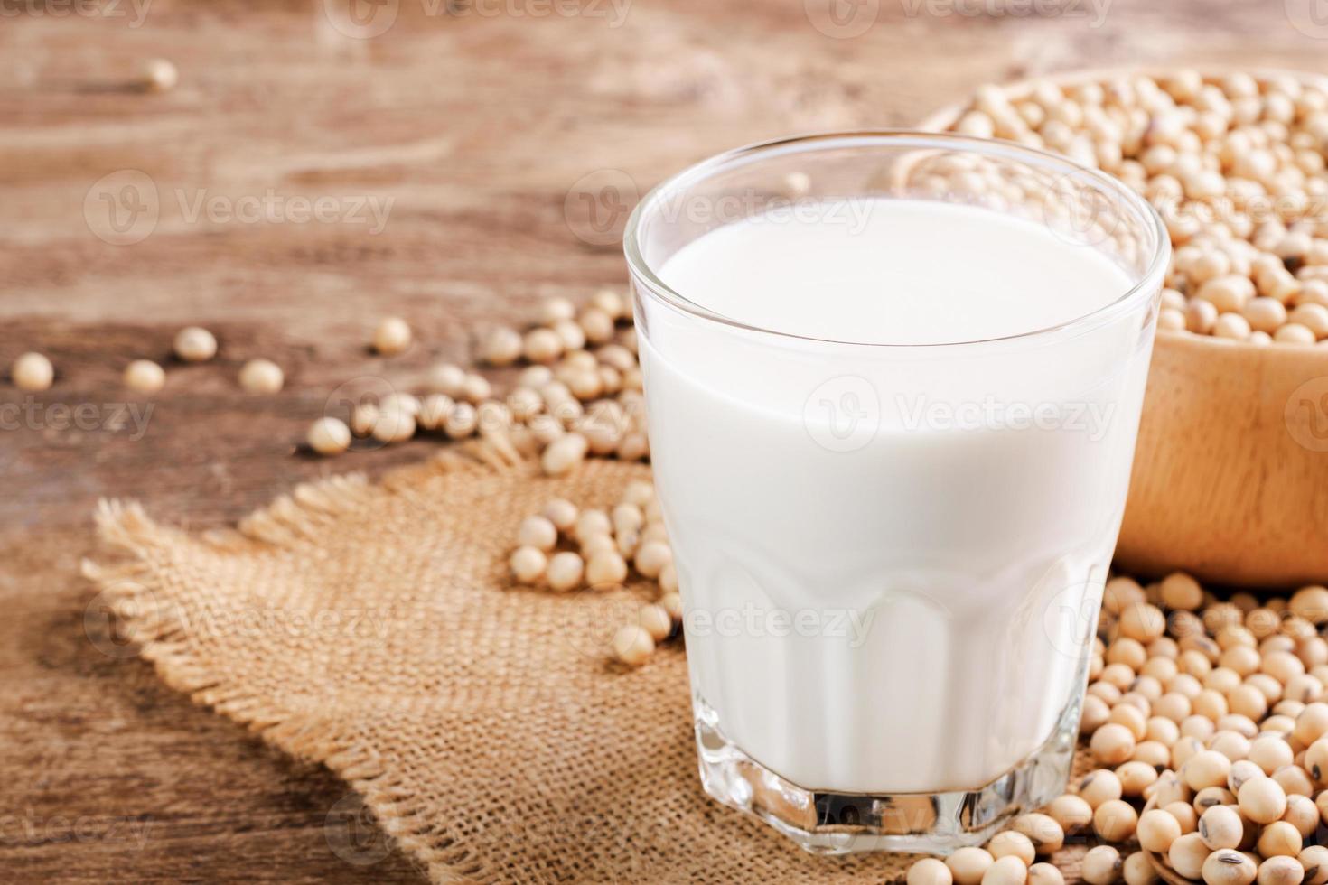 Leche de soja en un vaso con soja sobre una mesa de madera bebida orgánica alta en proteínas desayuno saludable productos agrícolas vegetariano foto