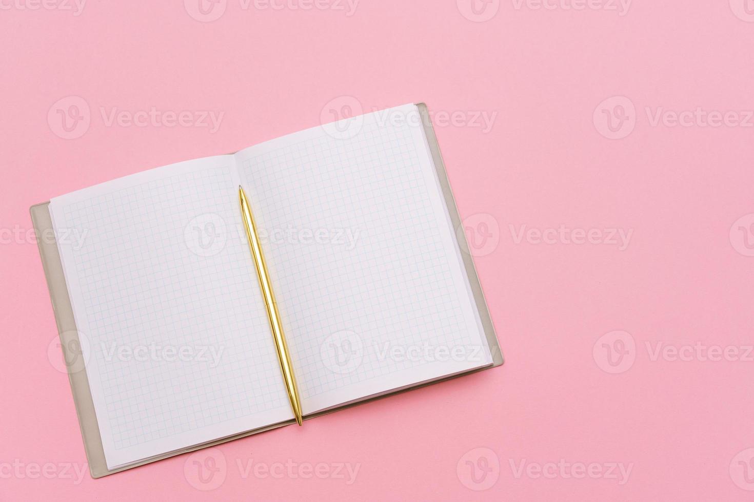 Notepad and gold pen on a pink background. Mock up, top view, copy space. photo