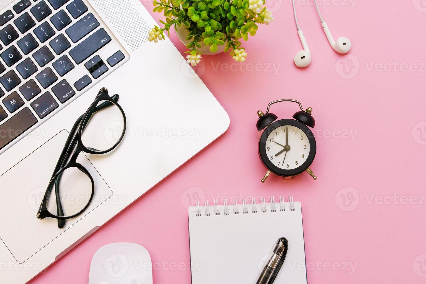 White notepad with office and personal accessories, black alarm clock and photo