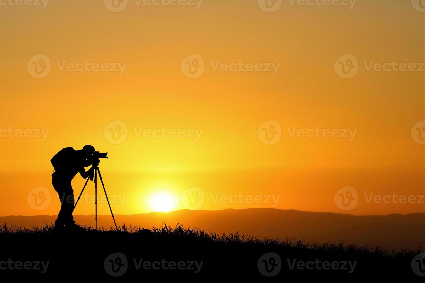 A professional photographer's silhouette is focused on shooting in a beautiful meadow. photo