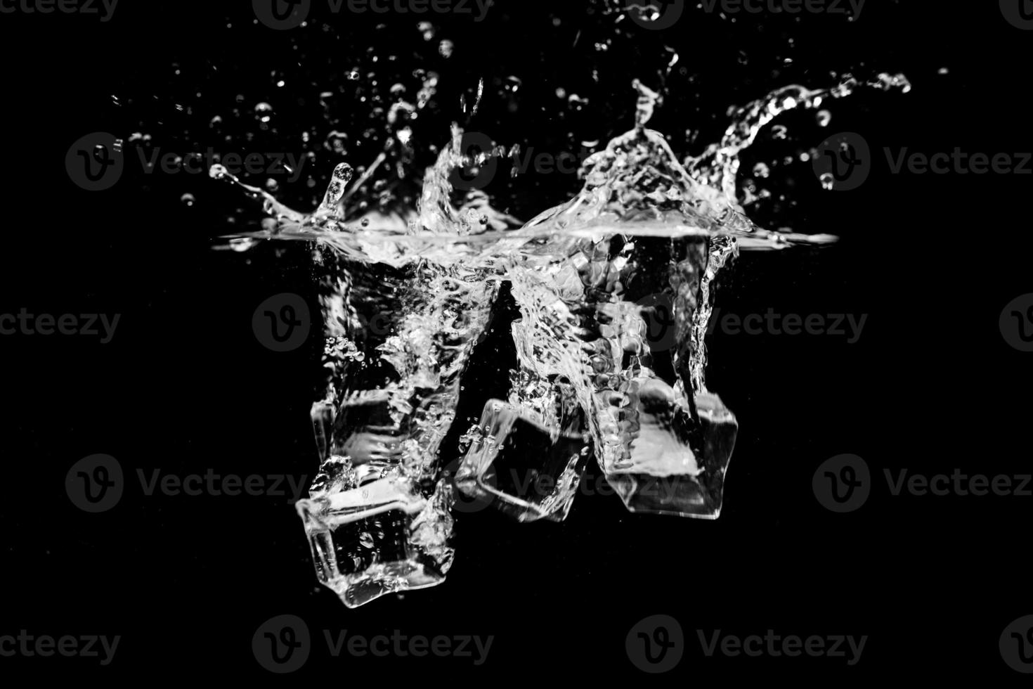 cubos de hielo en agua con burbujas sobre fondo negro foto