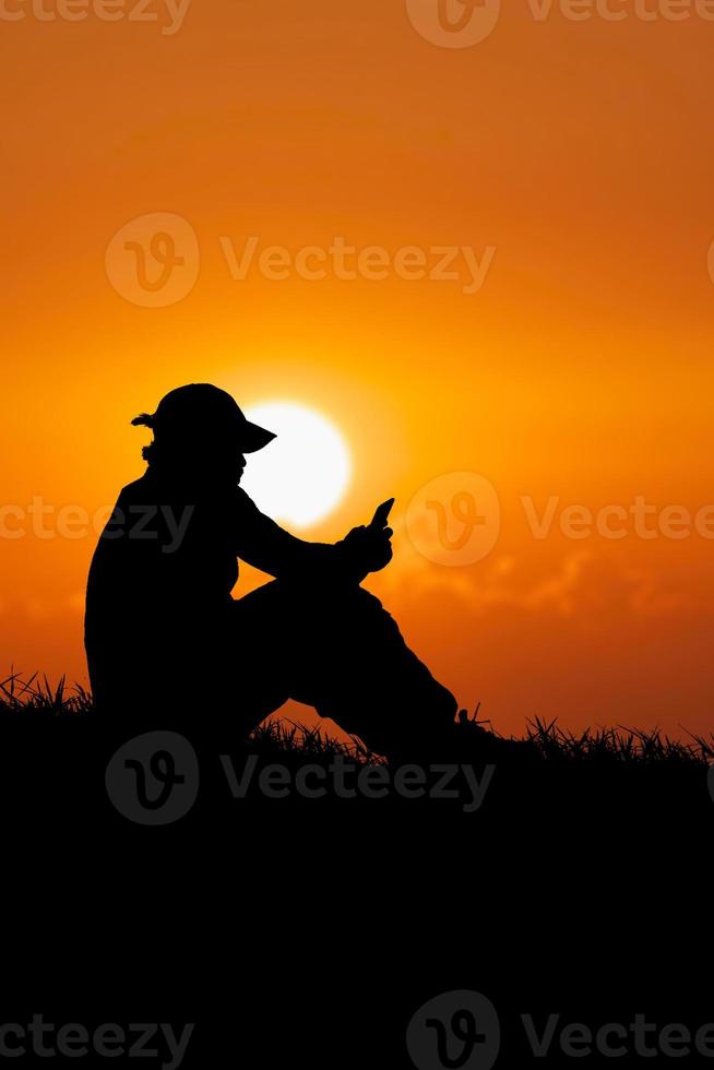 Silhouette of an unemployed man sitting and watching phone to find work photo