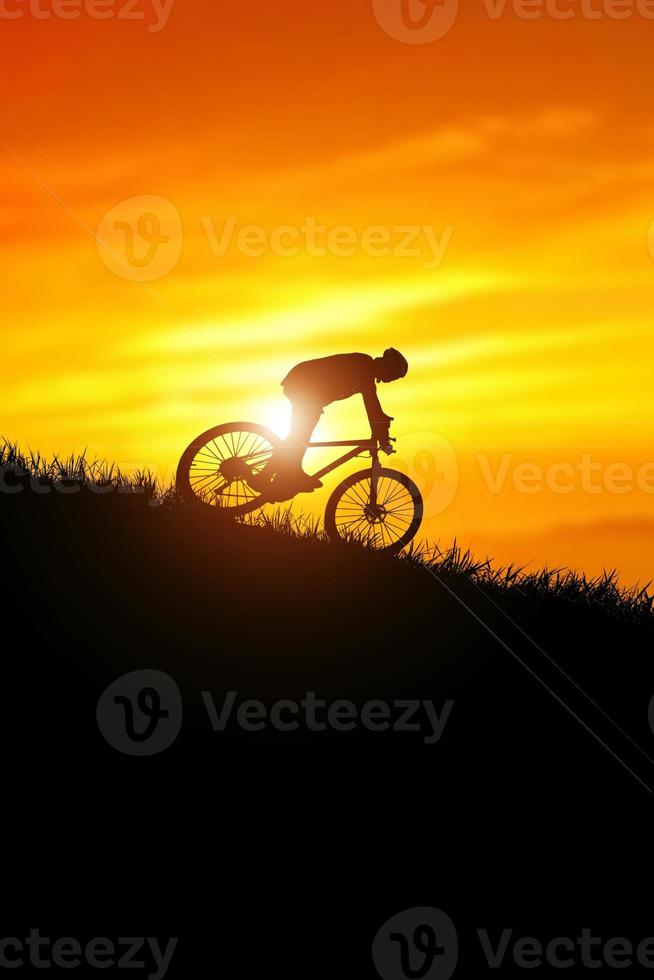 una silueta de un ciclista que desciende de la montaña por la noche. foto