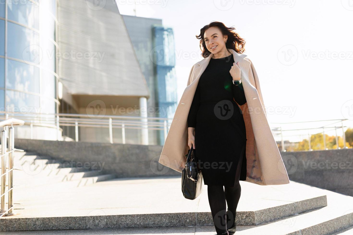 Businesswoman in stylish clothes walks up the steps of the office, career growth concept photo