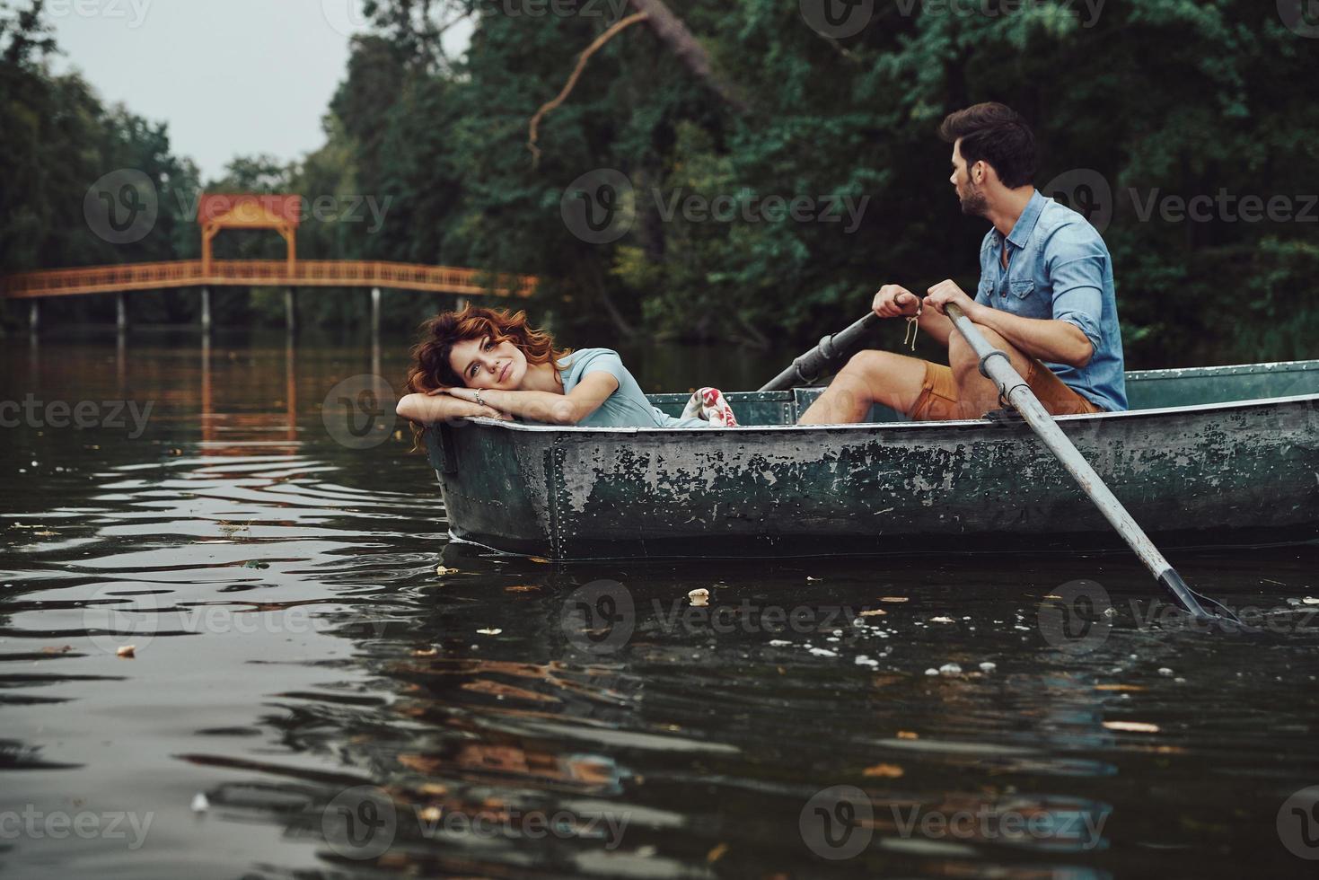 Enjoying summer. Beautiful young couple smiling while enjoying romantic date on the lake photo
