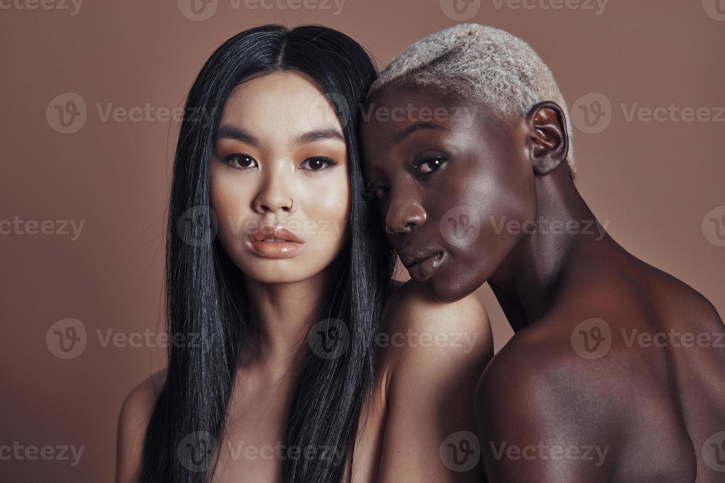 Multi-ethnic beauty. Attractive young women looking at camera while standing against brown background photo