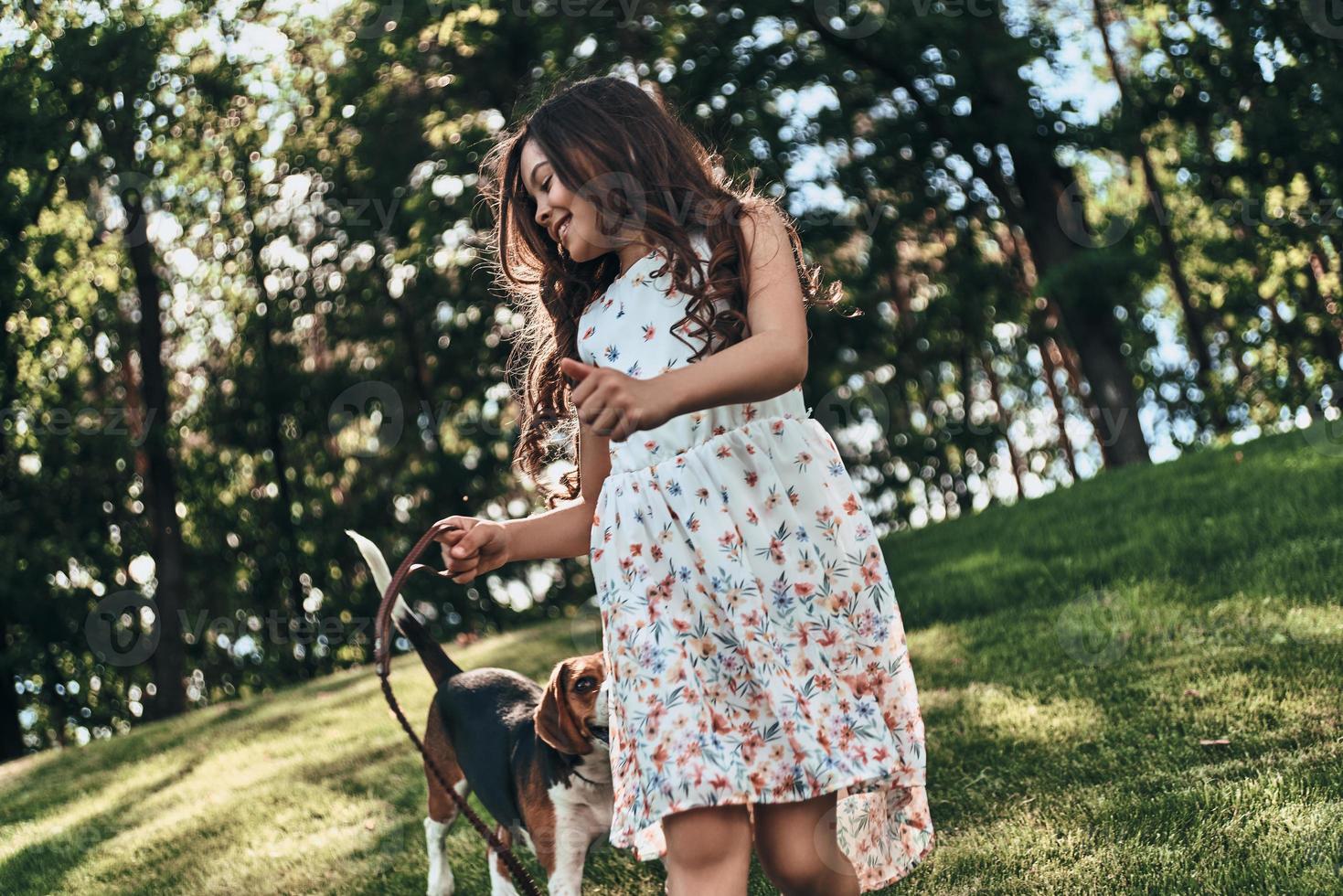 Cute little girl playing with her dog and smiling while walking outdoors photo