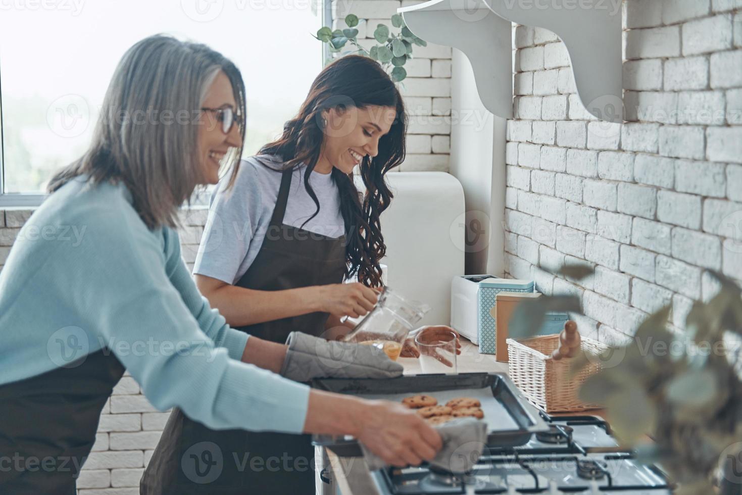 bella joven y su madre cocinan juntas mientras pasan tiempo en la cocina doméstica foto