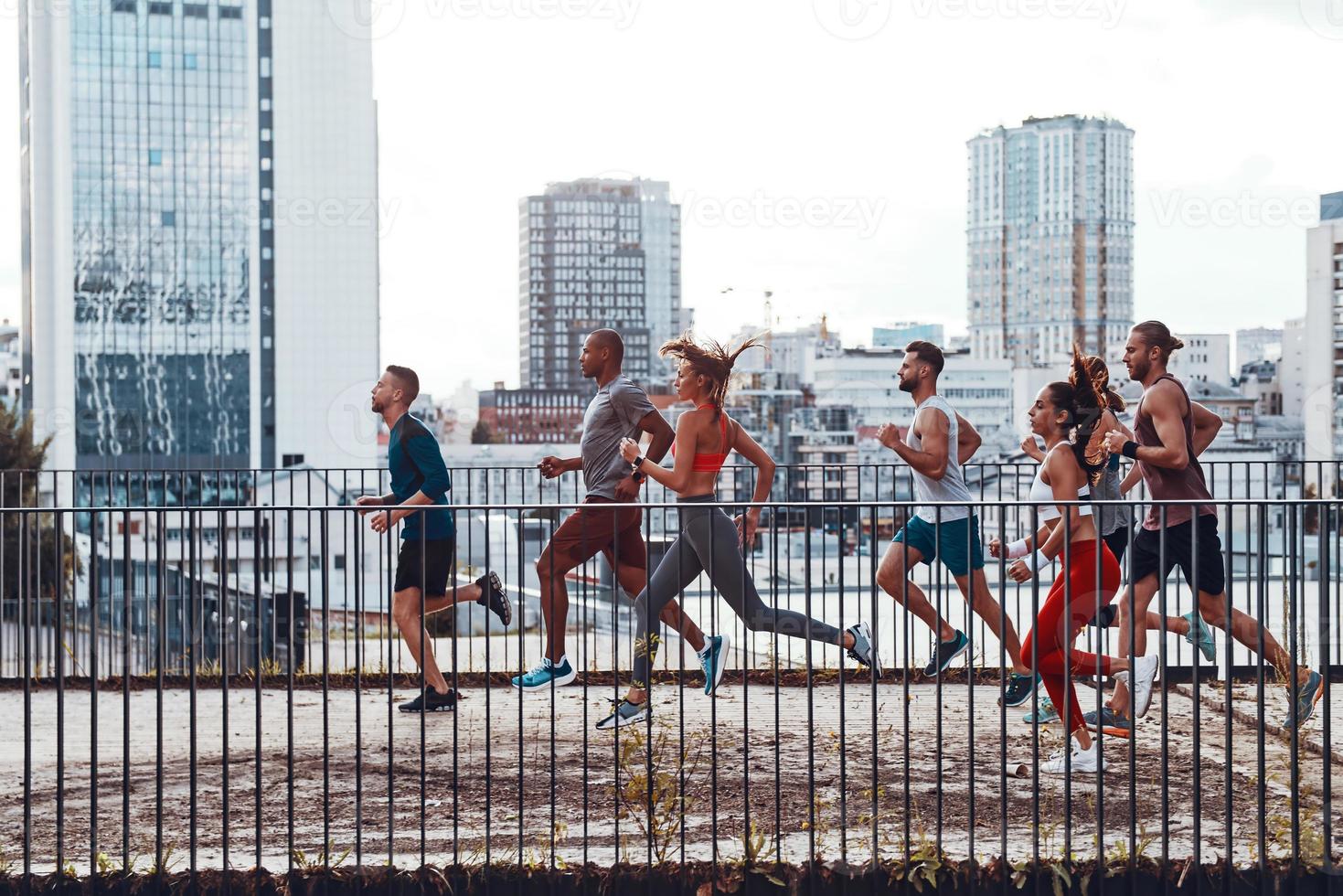 Full length of young people in sports clothing jogging while exercising on the bridge outdoors photo