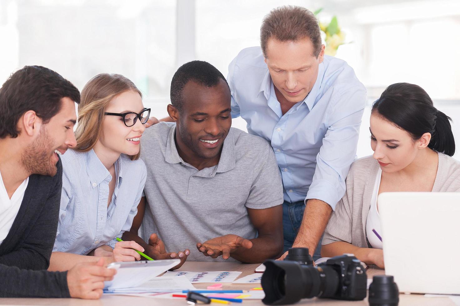 Discussing new project together. Group of cheerful business people sitting together at the table and discussing something photo