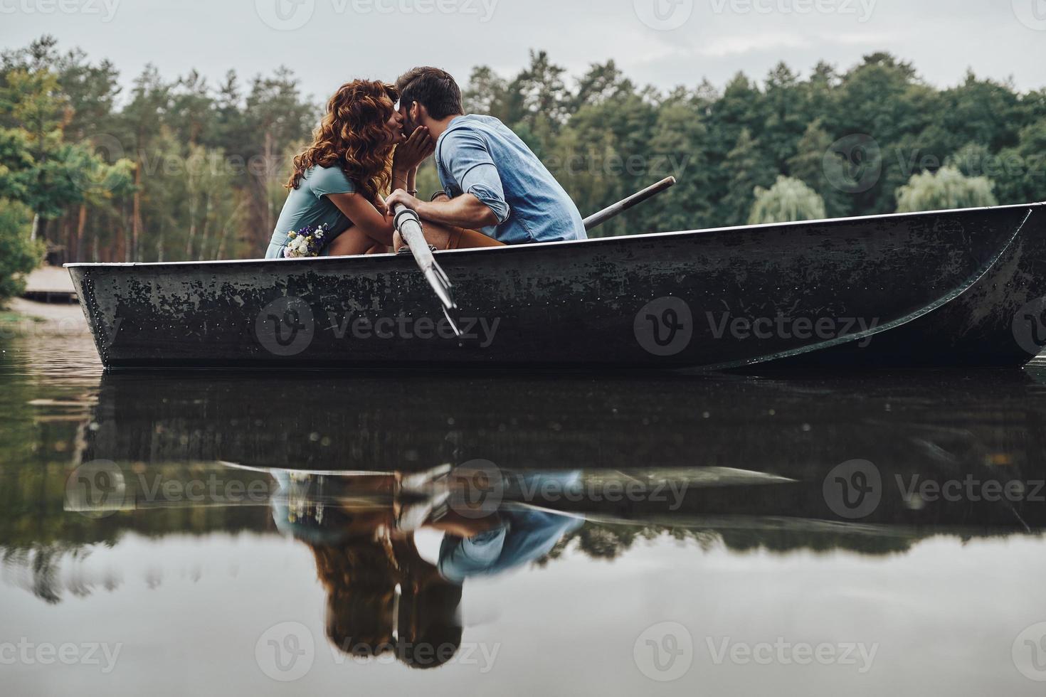 Real passion. Beautiful young couple kissing while rowing a boat during romantic date photo