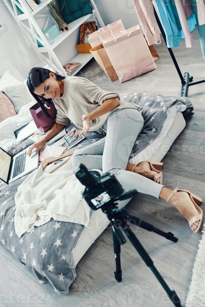 Top view of beautiful young woman in casual clothing making social media video while spending time at home photo