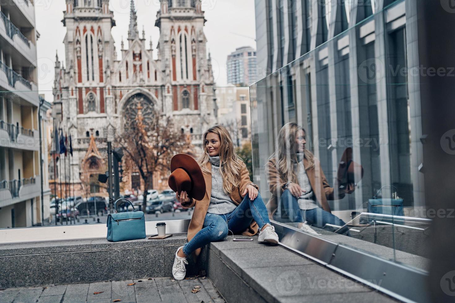 la música es su vida. atractiva joven escuchando música usando su teléfono inteligente mientras pasa tiempo sin preocupaciones en la ciudad foto