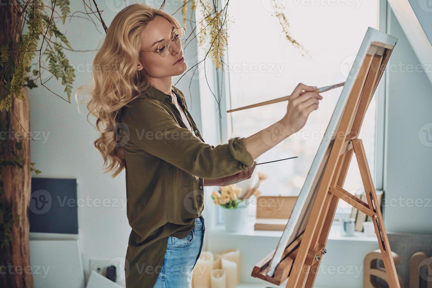 Side view of attractive young woman painting in art studio photo