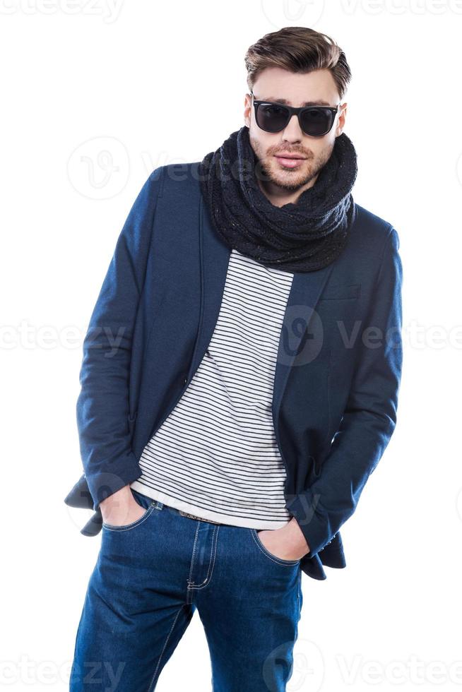Confident in his perfect look. Fashionable young man holding hands in pockets and looking at camera while standing against white background photo