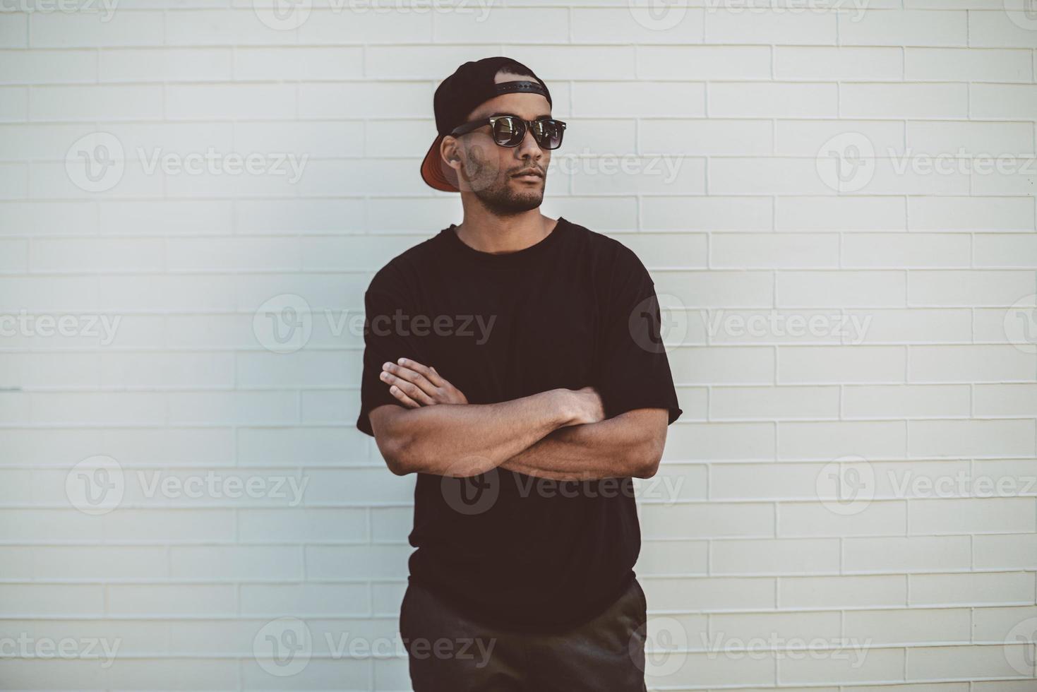 Casually handsome. Handsome young African man in casual clothes standing in front of the brick wall outdoors photo