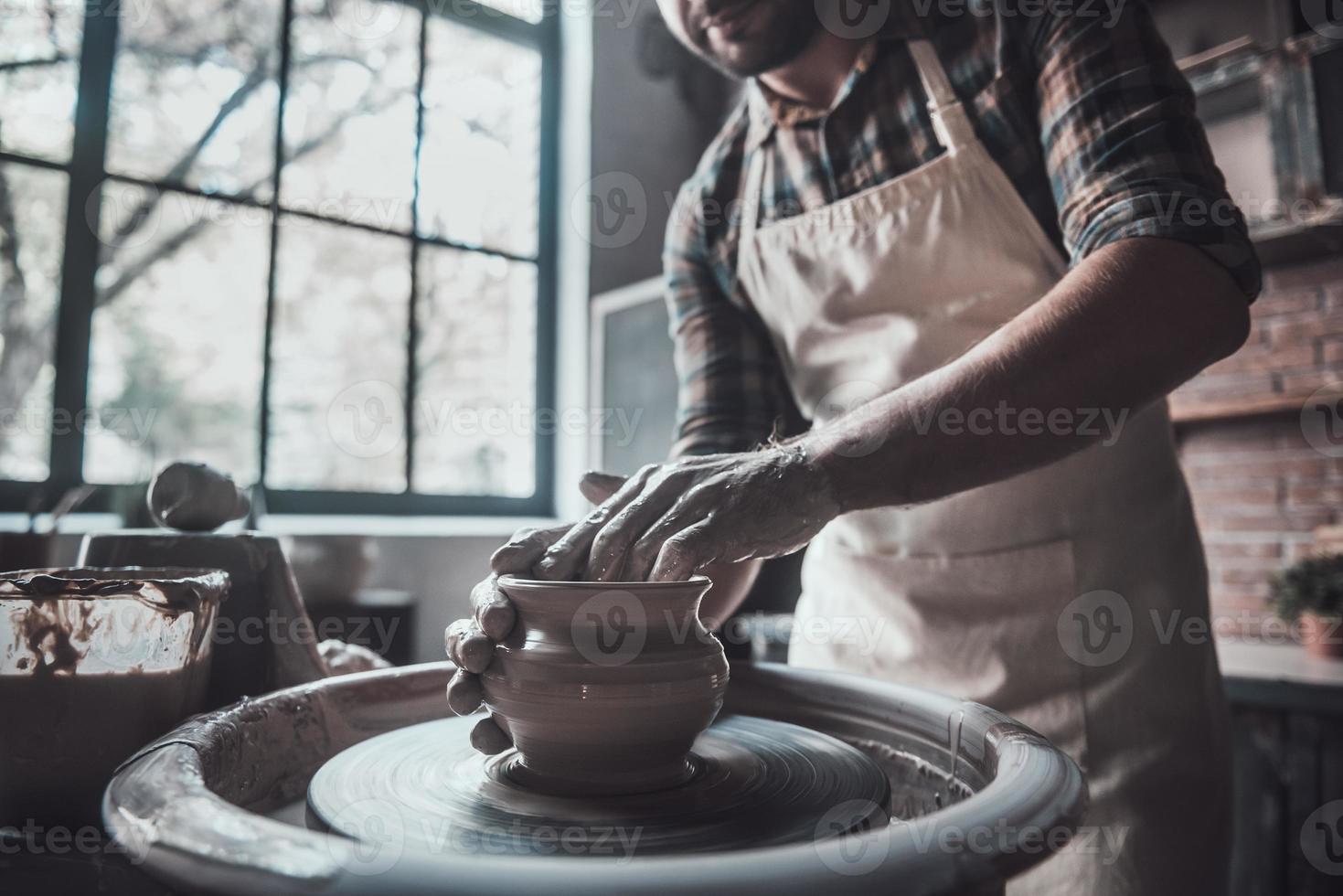 Potter at work. Low angle view of man making ceramic pot on the pottery wheel photo