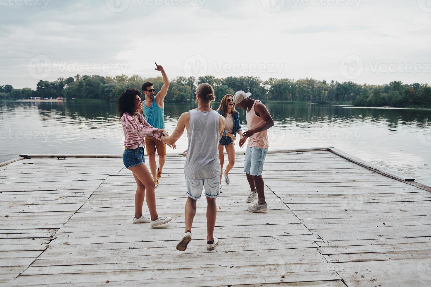 Best friends. Full length of young people in casual wear smiling and gesturing while enjoying beach party photo