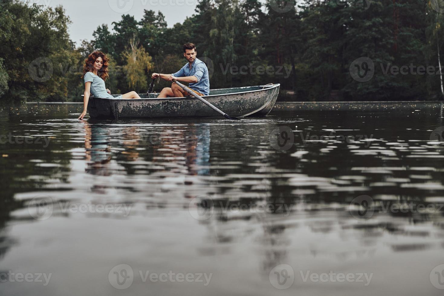 simplemente relajarse. hermosa pareja joven disfrutando de una cita romántica mientras rema en un bote foto
