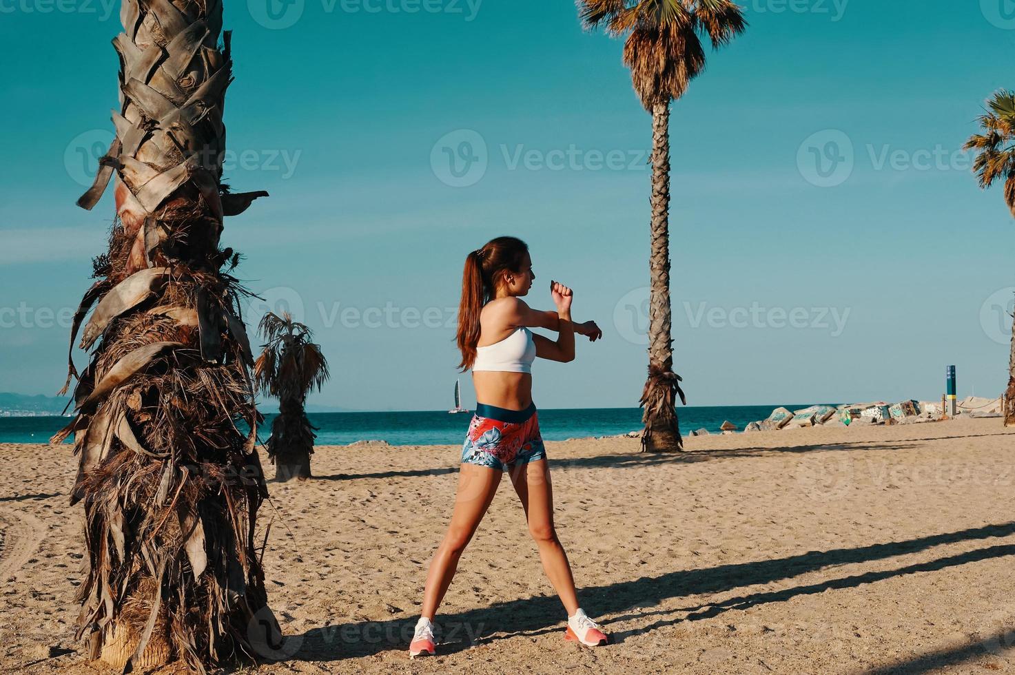 Fit and healthy. Full length of beautiful young woman in sports clothing stretching while warming up outdoors photo