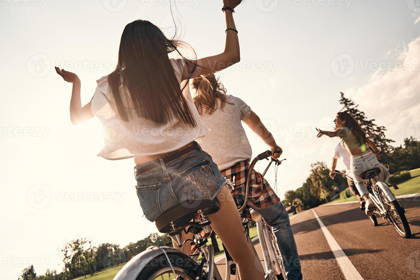 feliz de estar cerca. vista trasera de los jóvenes en ropa casual en bicicleta juntos mientras pasan tiempo sin preocupaciones al aire libre foto