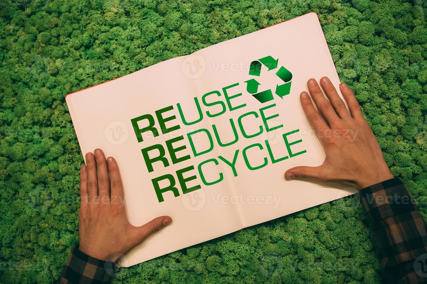 Live green. Top view close-up image of man holding hands on his notebook with text and recycle symbol at moss background photo